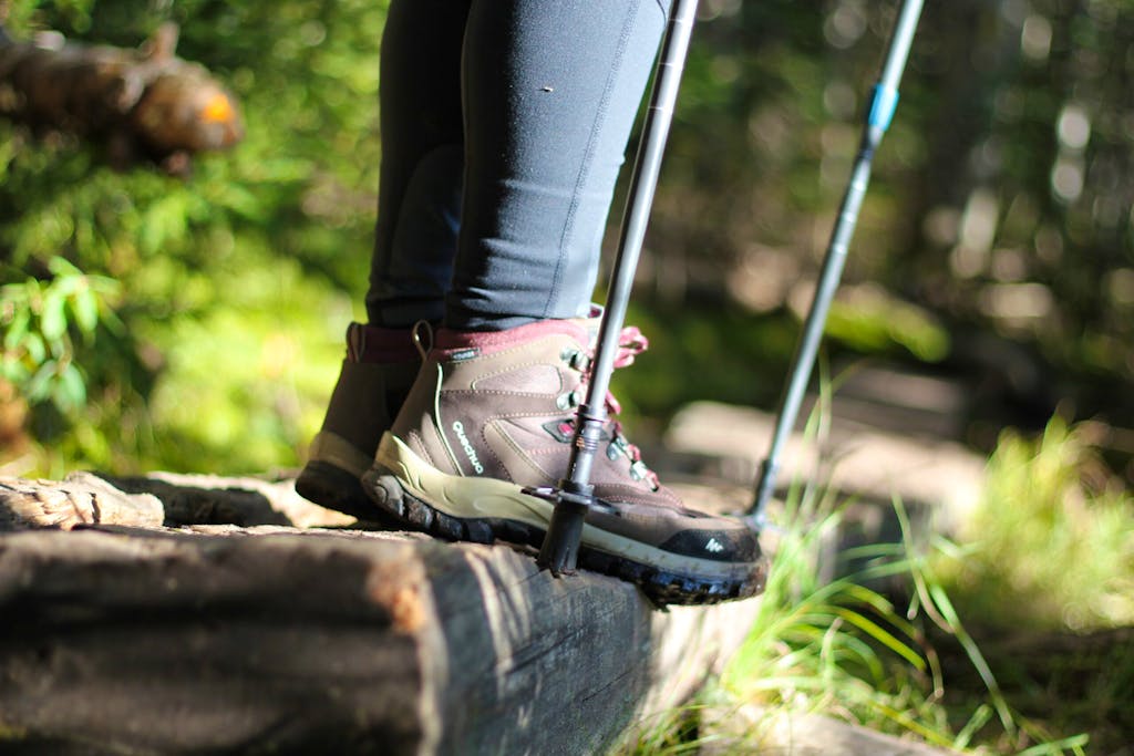 Hiker with good hiking boots and trekking poles standing on top of a wooden stairs 