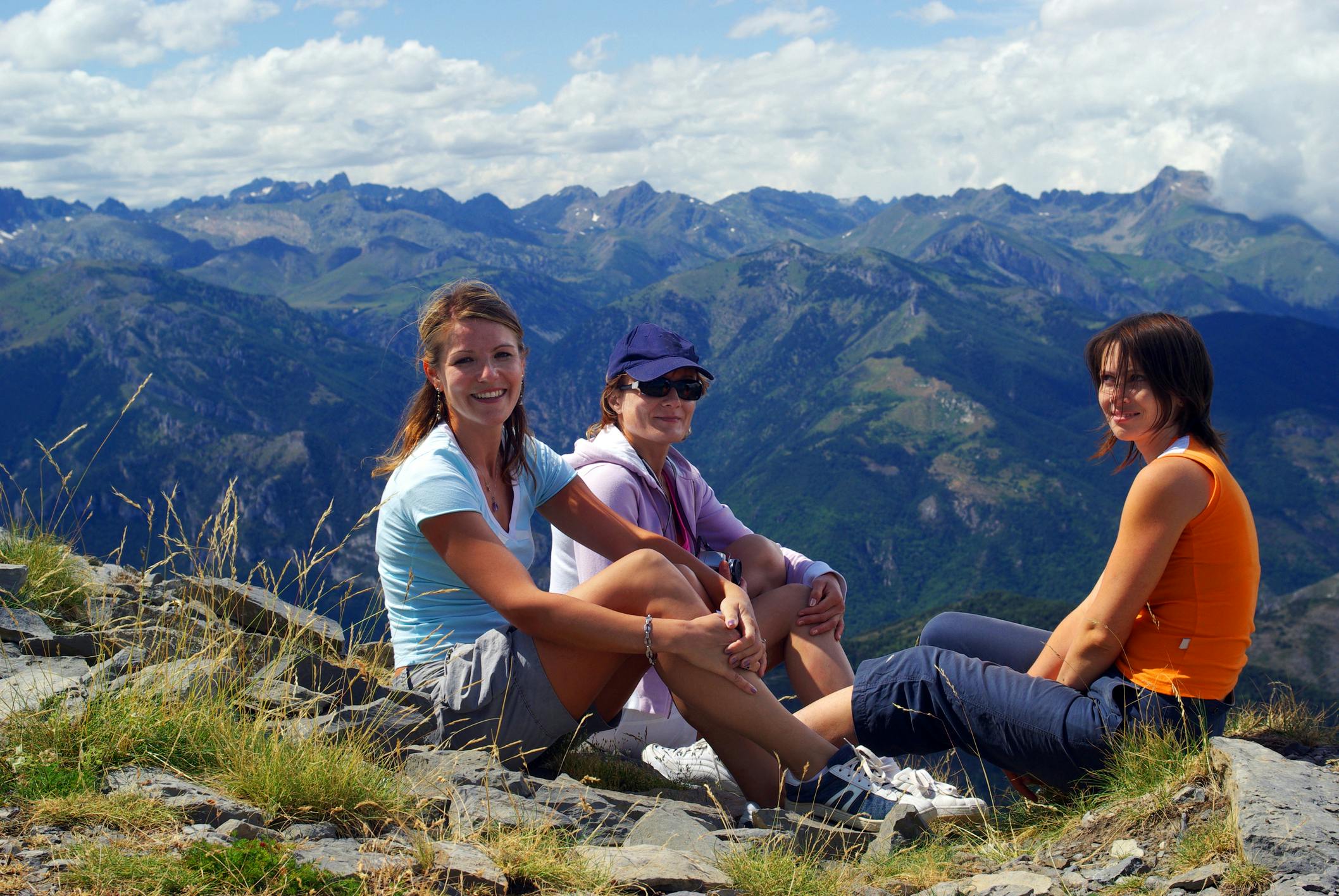 Three women sitting on a rock.