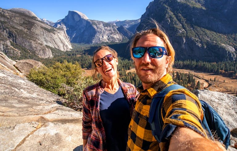 Couple enjoying a day hike in Yosemite National Park with views of El Capitan, Half Dome, and Sentinel Rock