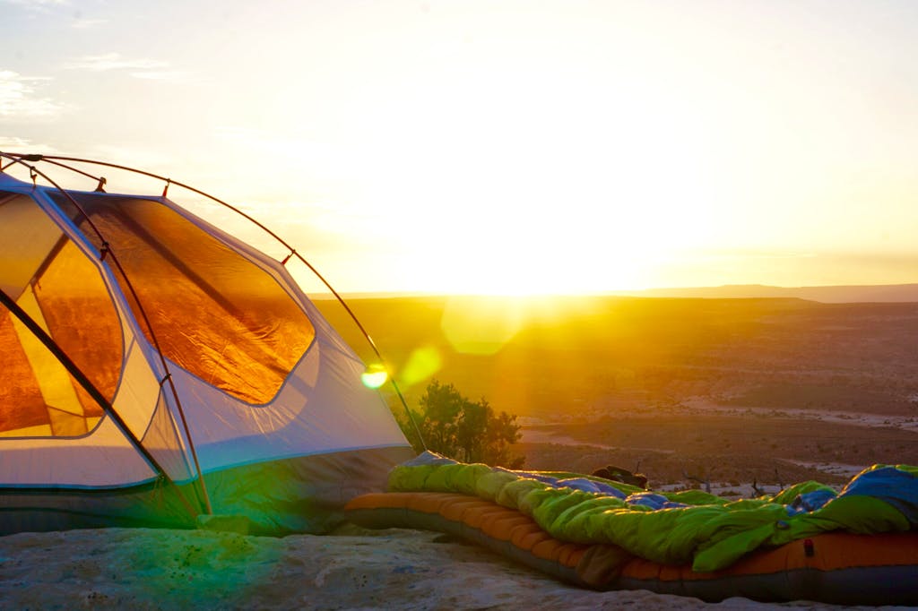 Colorful sleeping bags and camping tent in campground overlooking nature landscape