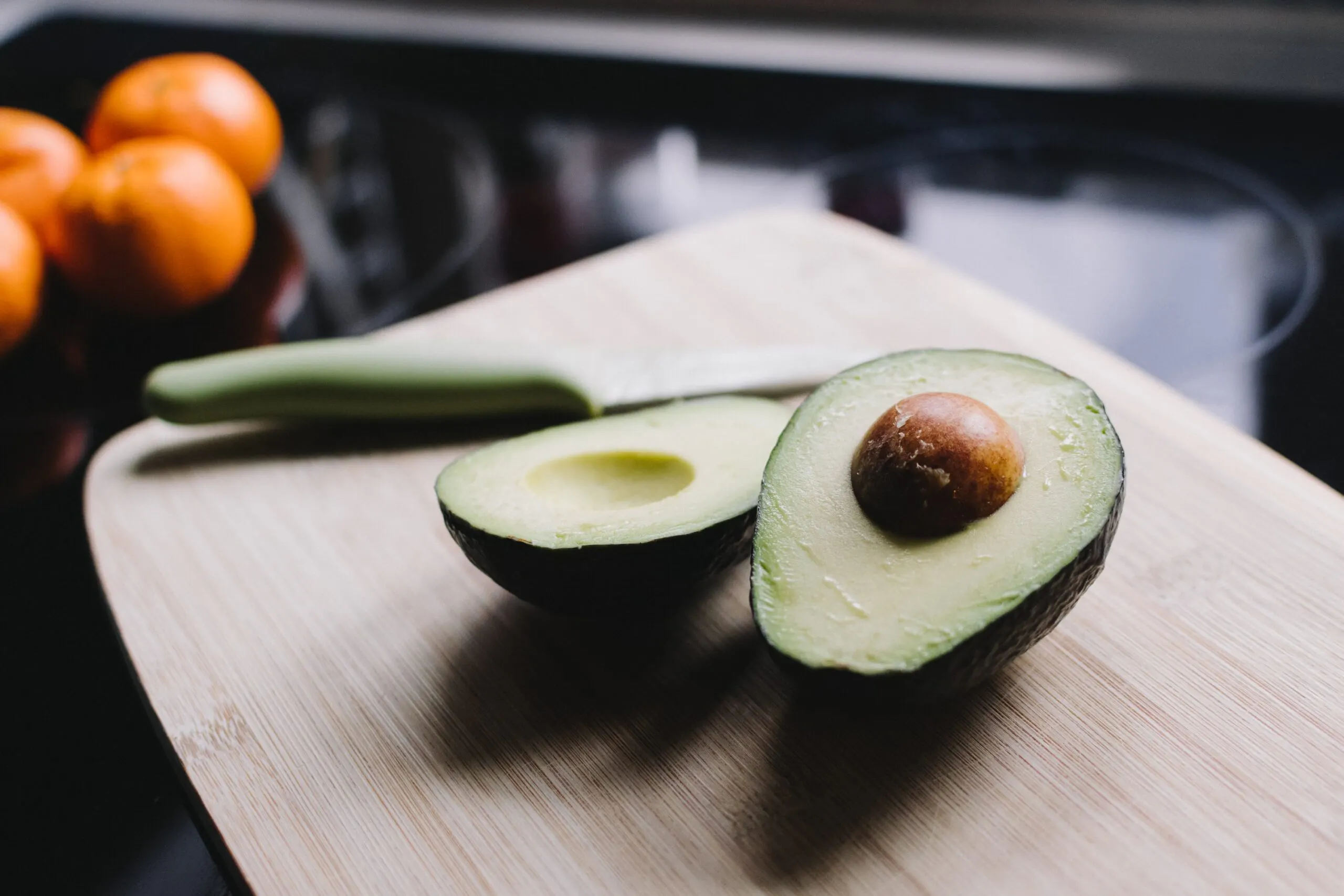 Avocadoes cut in half on a cutting board in the kitchen