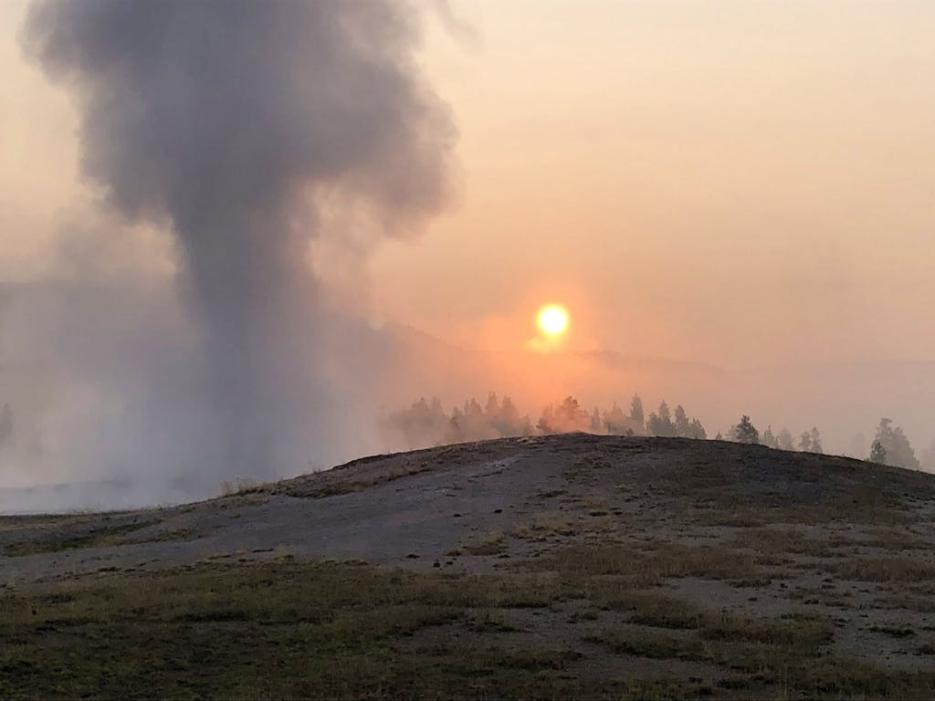 A foggy view of the Old Faithful during a sunrise at Yellowstone National Park