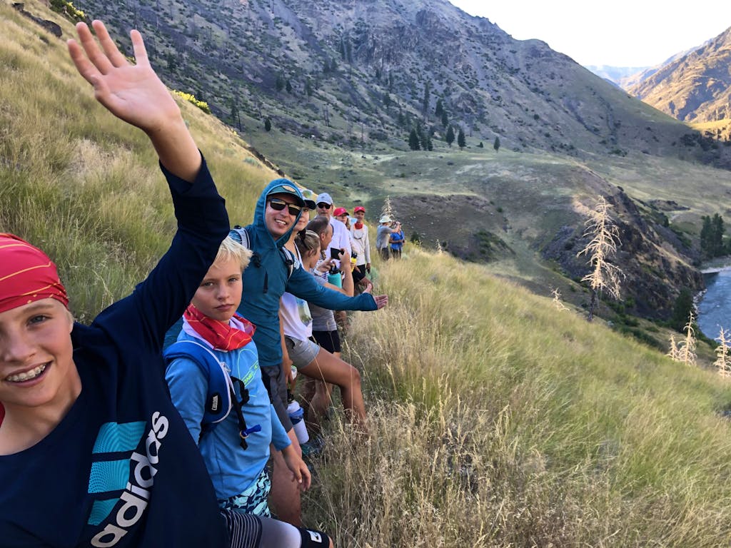 A group of hikers waving their hands on the middle fork of a mountain in Idaho.