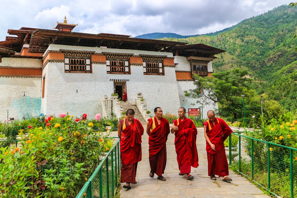 Group of monks in their traditional clothes walking in a garden next to a Buddhist monastery in Bhutan