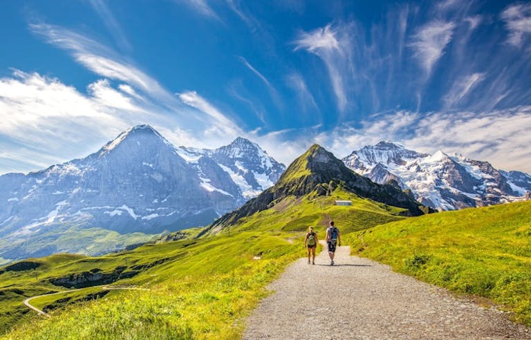 two female and male hikers following  alpine trails to mountain villages in the Alps 