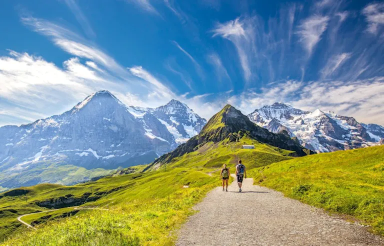 two female and male hikers following alpine trails to mountain villages in the Alps