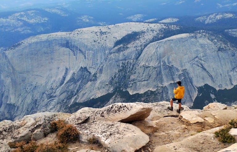 male solo hiker arriving at top of mountain in guided tour of Yosemite National Park