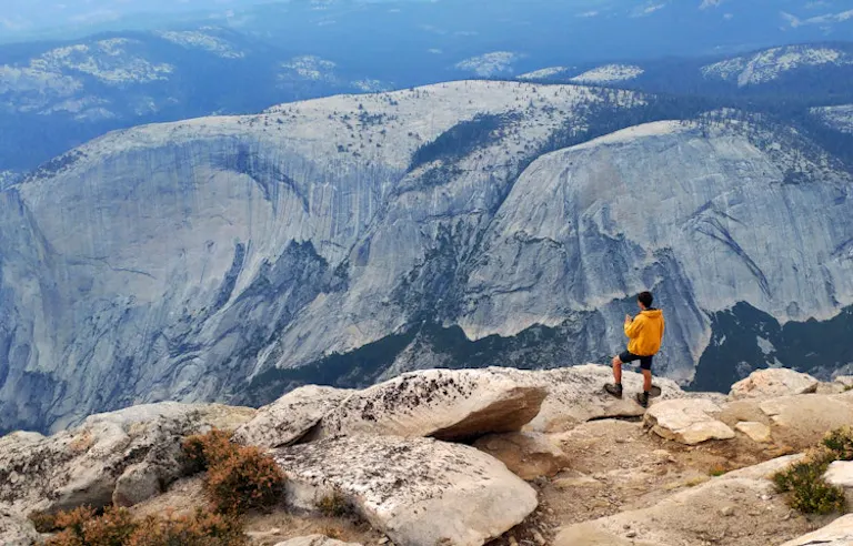 male solo hiker arriving at top of mountain in guided tour of Yosemite National Park