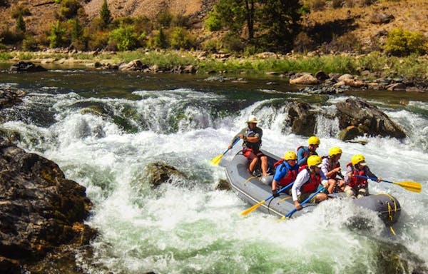 A group of people rafting down rapids in a river.