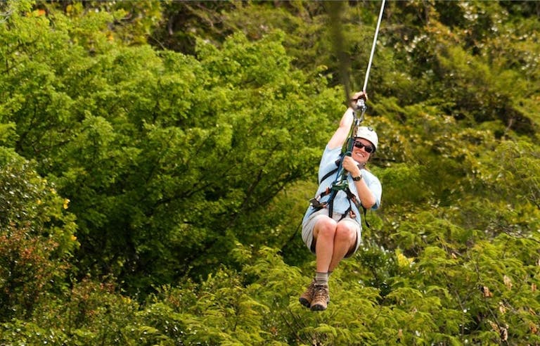 female traveler zipping through the treetops on an innovative course in the tropical forests of Costa Rica in Central America