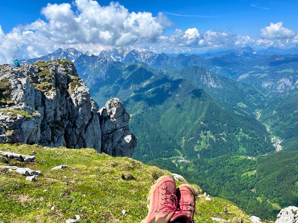 Hiker with red hiking shoes sitting near the ledge in the Raduha Mountain Range in Slovenia