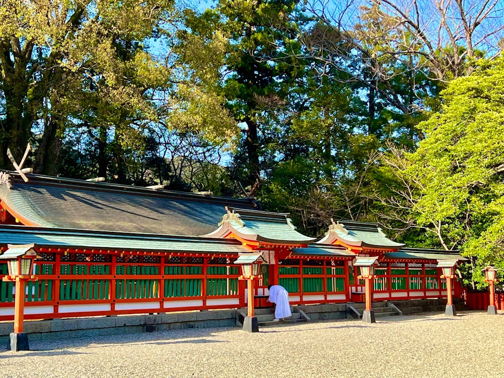 Travelers bowing respectfully at an ancient temple along the Kumano Kodo hiking trail