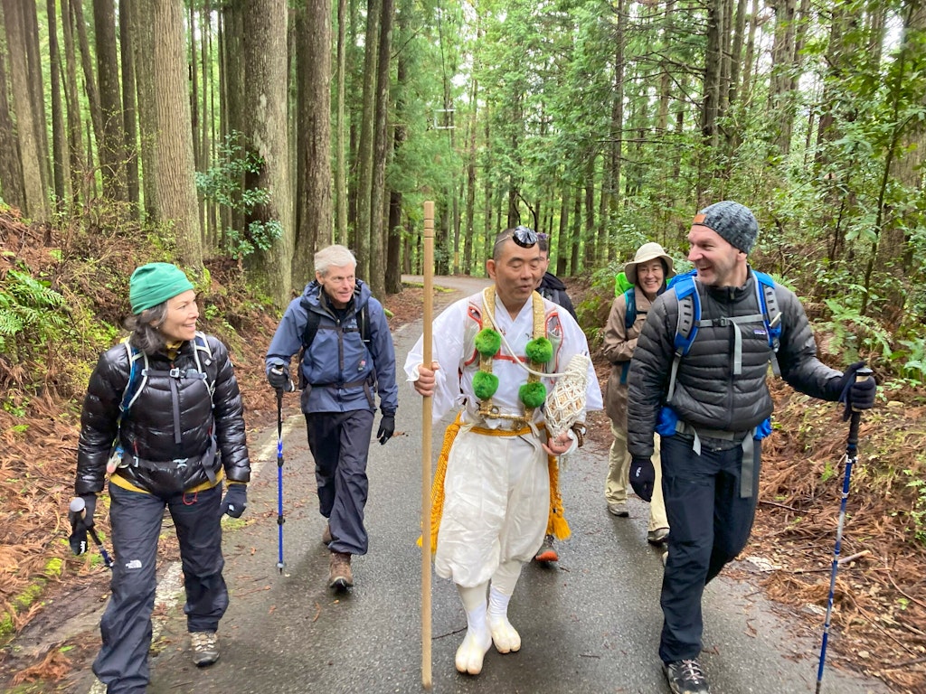 Group of travelers hiking with a Buddhist monk along the Kumano Kodo Ancient Japanese Pilgrimage Route