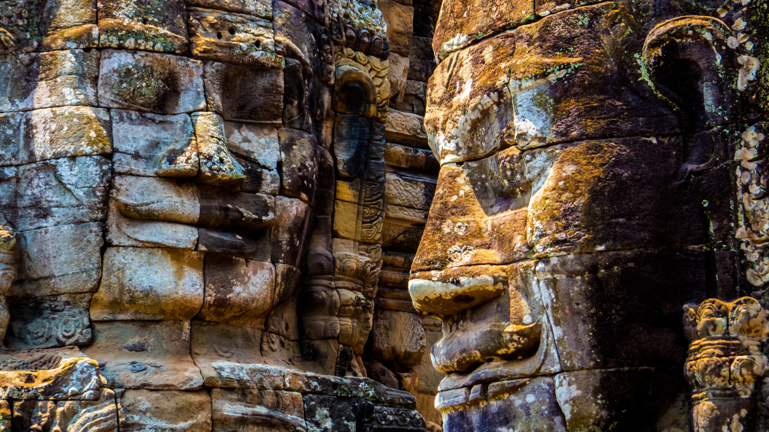Serenely smiling faces beaming down at travelers on stone towers throughout the Bayon Temple in Angkor Wat