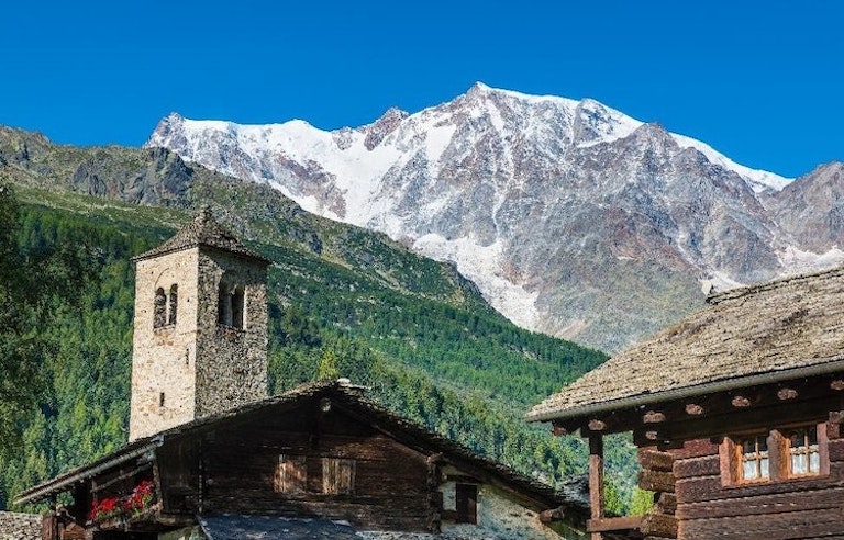 A village in the alps with snowy mountains in the background.