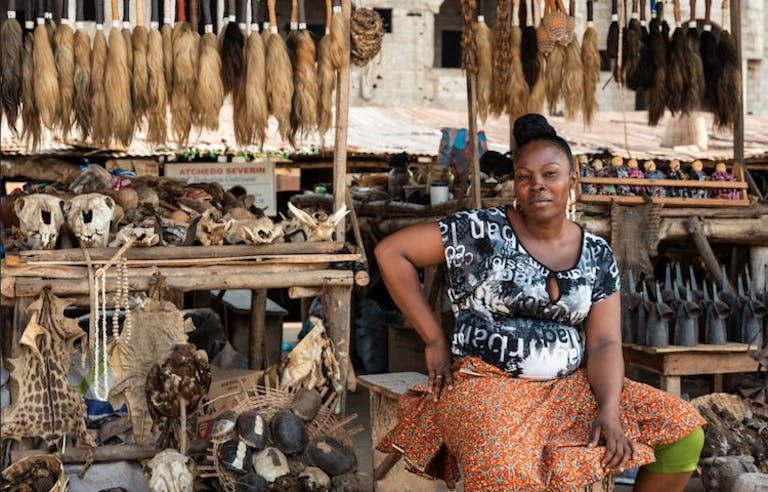 Traditional woman in West Africa boasting her architecture and items to tourists