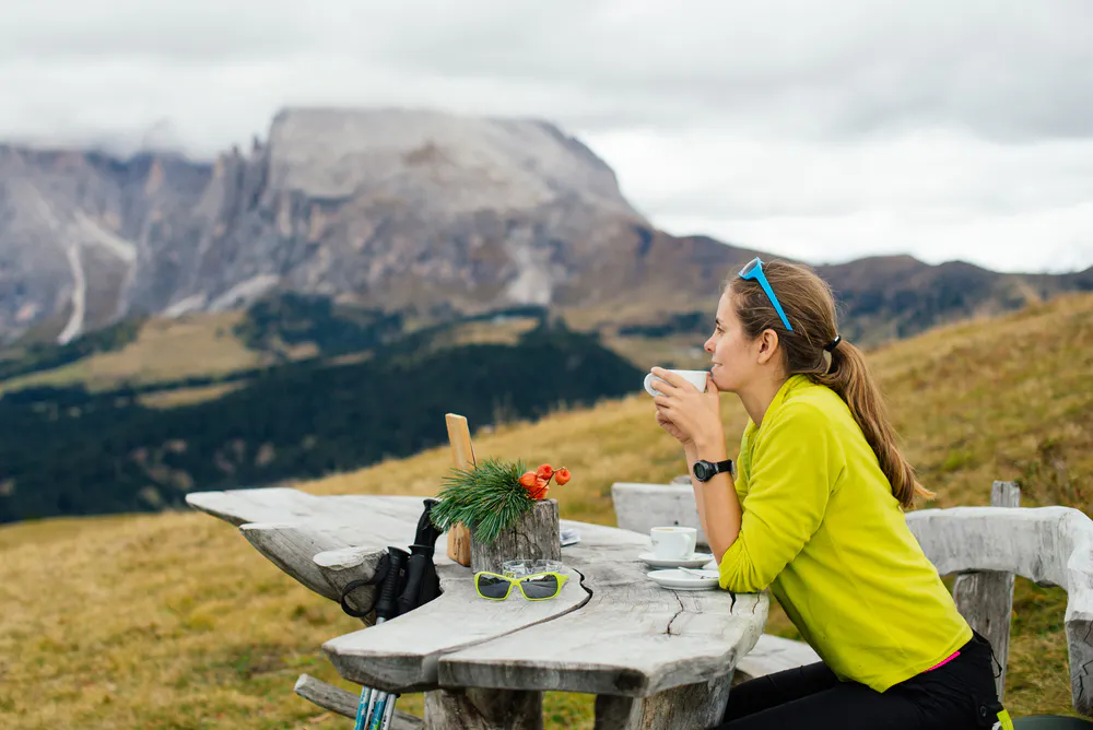 Girl tourist drinking delicious coffee and admiring the views of the Dolomites in the Alps region in Italy, Europe