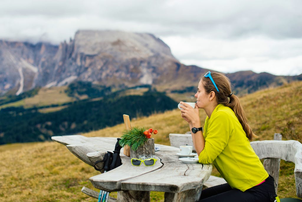 Girl tourist drinking delicious coffee and admiring the views of the Dolomites in the Alps region in Italy, Europe