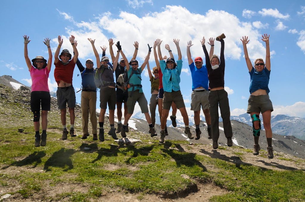 happy group of guided hikers who are on an Alps hiking adventure in Switzerland, Europe