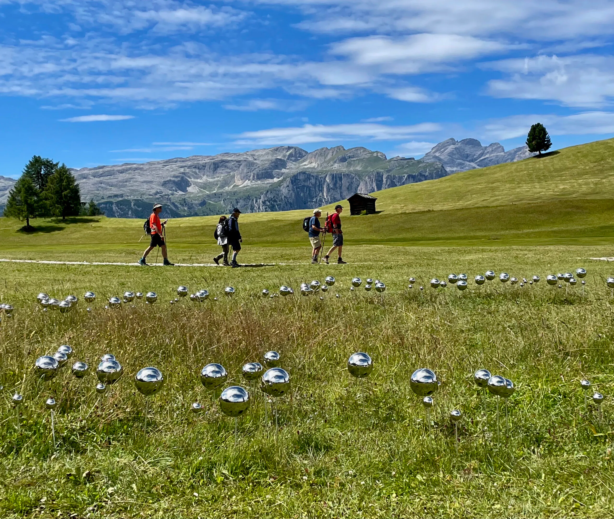 A group of people walking through a field of silver balls.