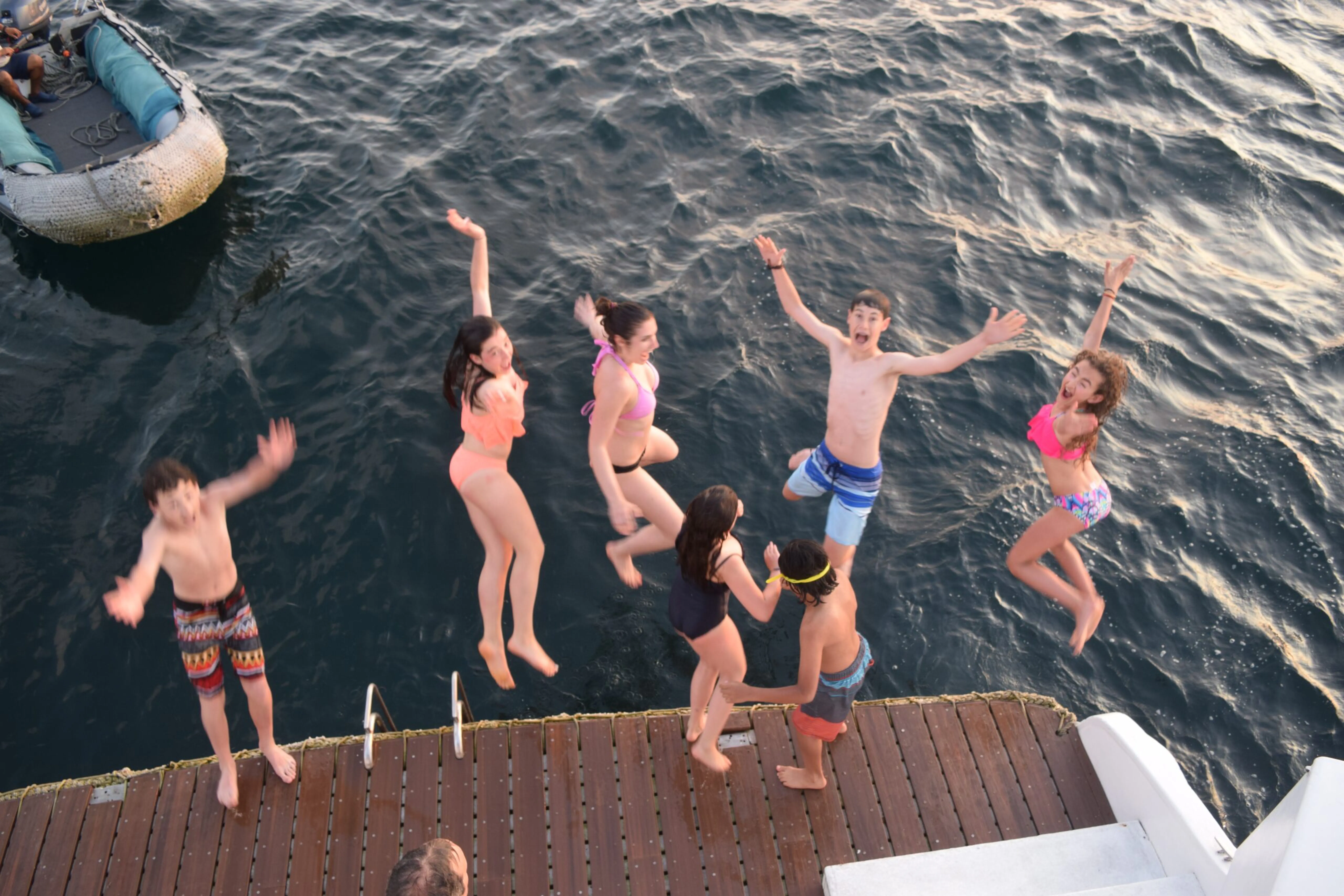 A group of people jumping off a boat.
