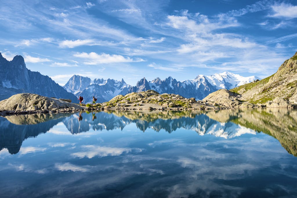 Hikers reflected in Lac Blanc on the Tour du Mont Blanc trekking route in the French Alps near Chamonix