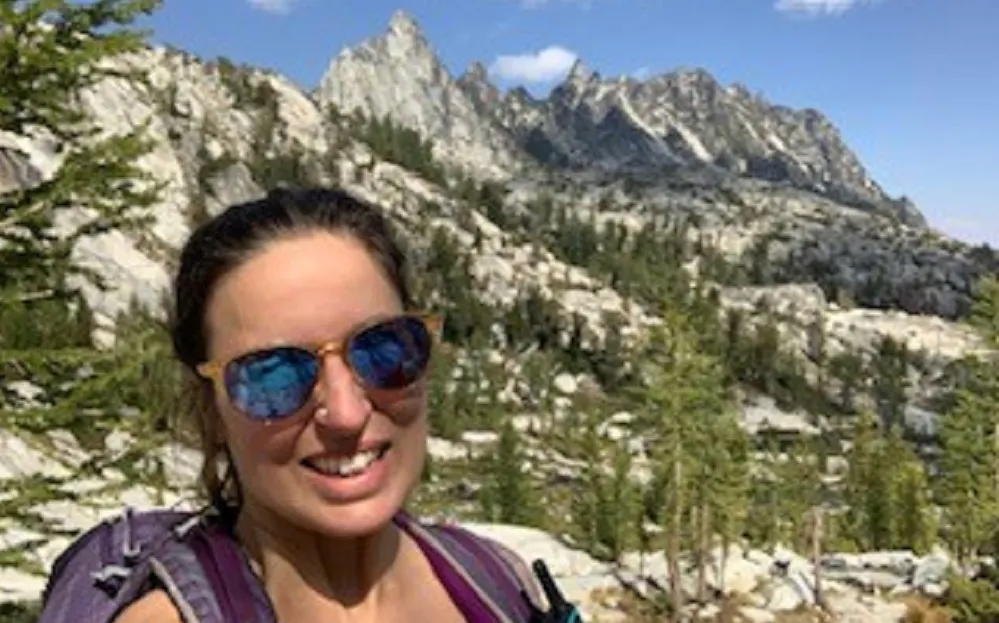 female hiker with sunglasses with a backdrop of natural mountain scenery in USA