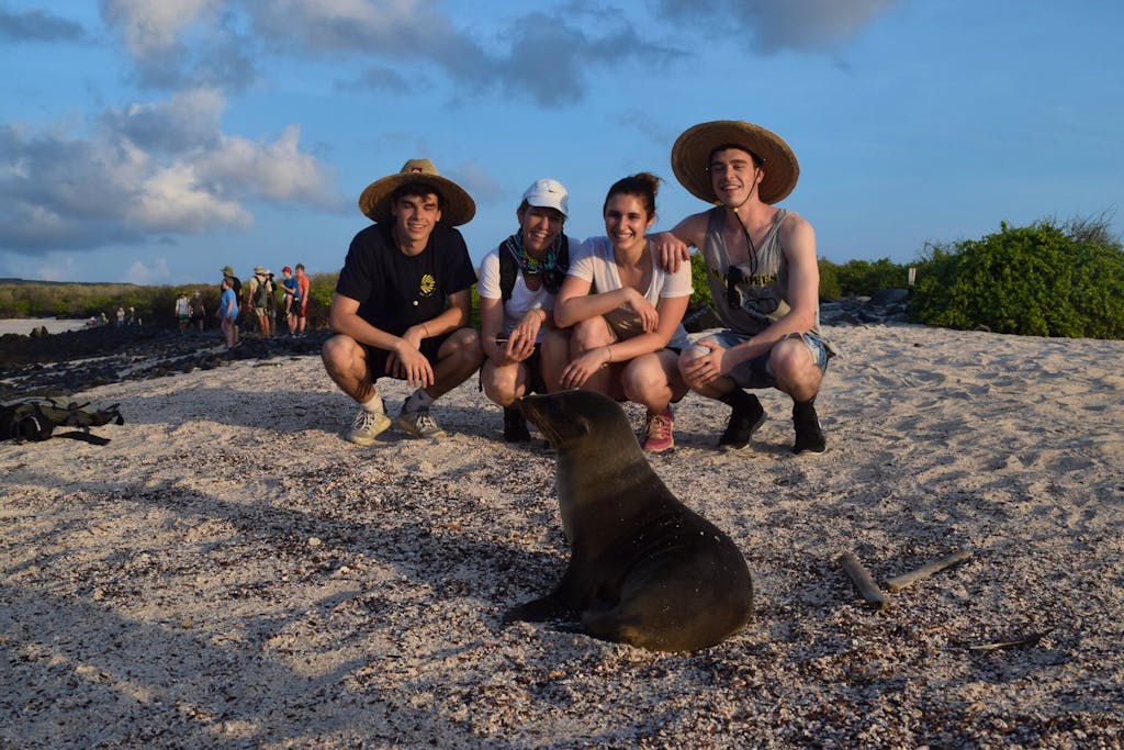 two girls and two guys staring at a Galapagos seal on the Santa Cruz island of the Galapagos in Ecuador