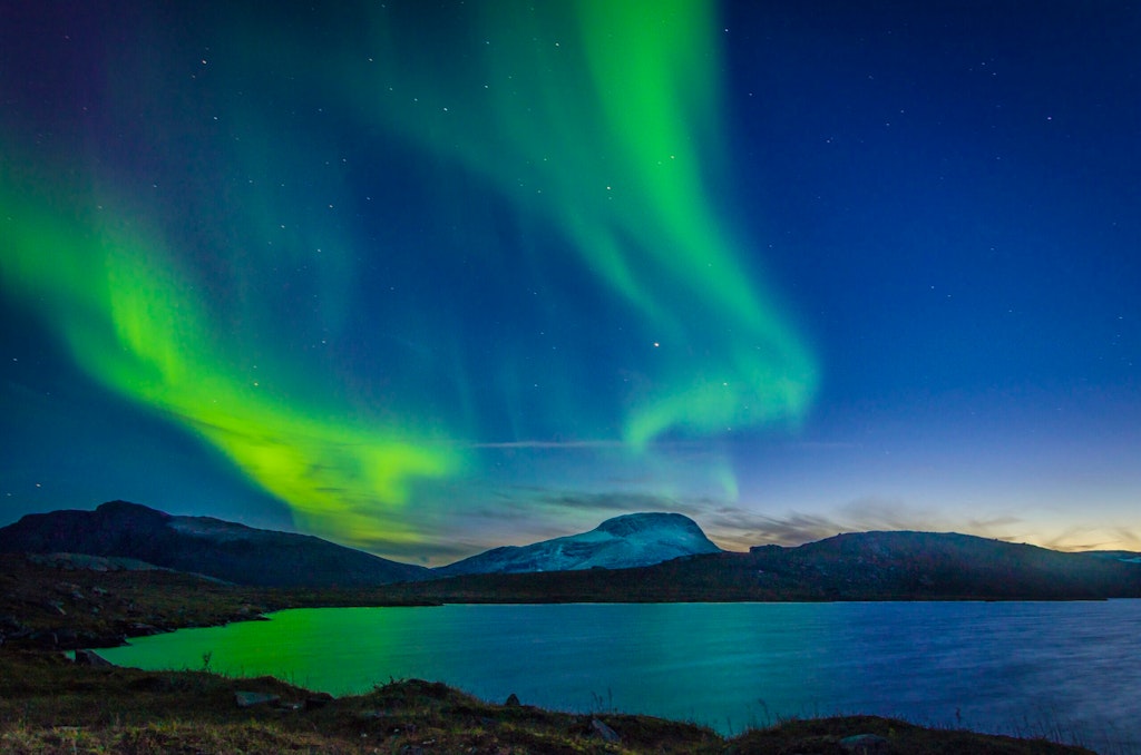 Aurora burealis sighting in Sweden near a mountain with a lake