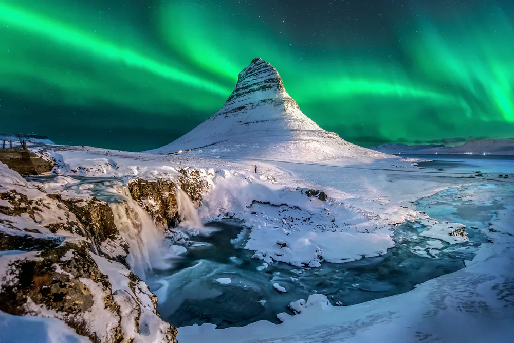 celestial northern lights appear over Mount Kirkjufell in Iceland.