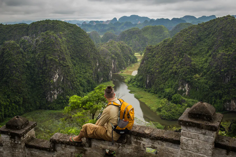 Stock Photo ID: 721379389 Tourists traveling in boat along the Ngo Dong River and taking picture of the Tam Coc, Ninh Binh, Vietnam. Amazing view.Terraced rice field landscape.