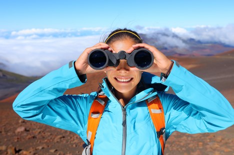female solo hiker using travel gadgets like binoculars on their trip