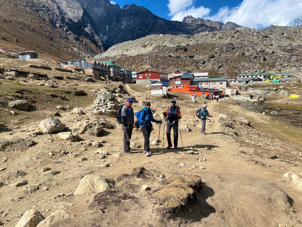 Group of hikers with trekking poles on challenging trek to Everest Base Camp stops near Gorak Shep