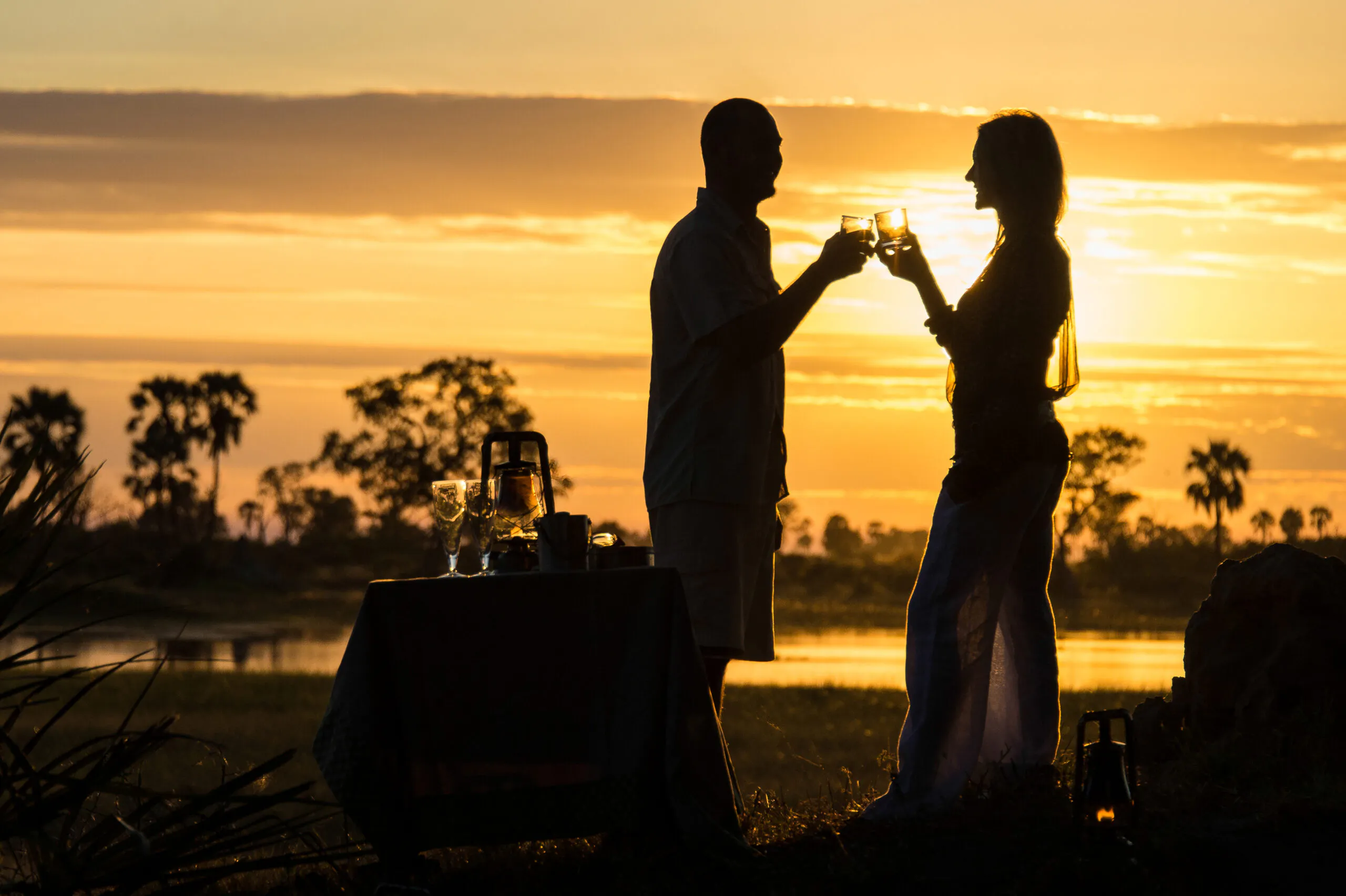 Female and male travelers enjoying sundowners at Okavango Delta, Botswana, Africa