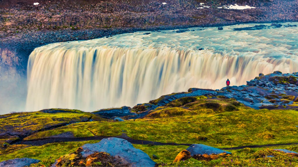 female solo traveler hiking to Ireland's legendary natural wonders like the Dettifoss Waterfall in the summertime in Iceland, Europe