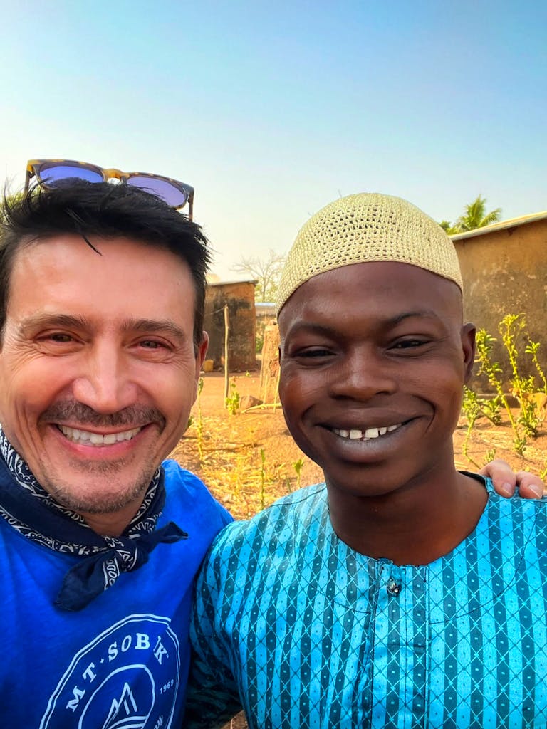 Massimo smiling widely with a nomadic camp of the Fulani, the largest tribe of Zebu cow herders in West Africa