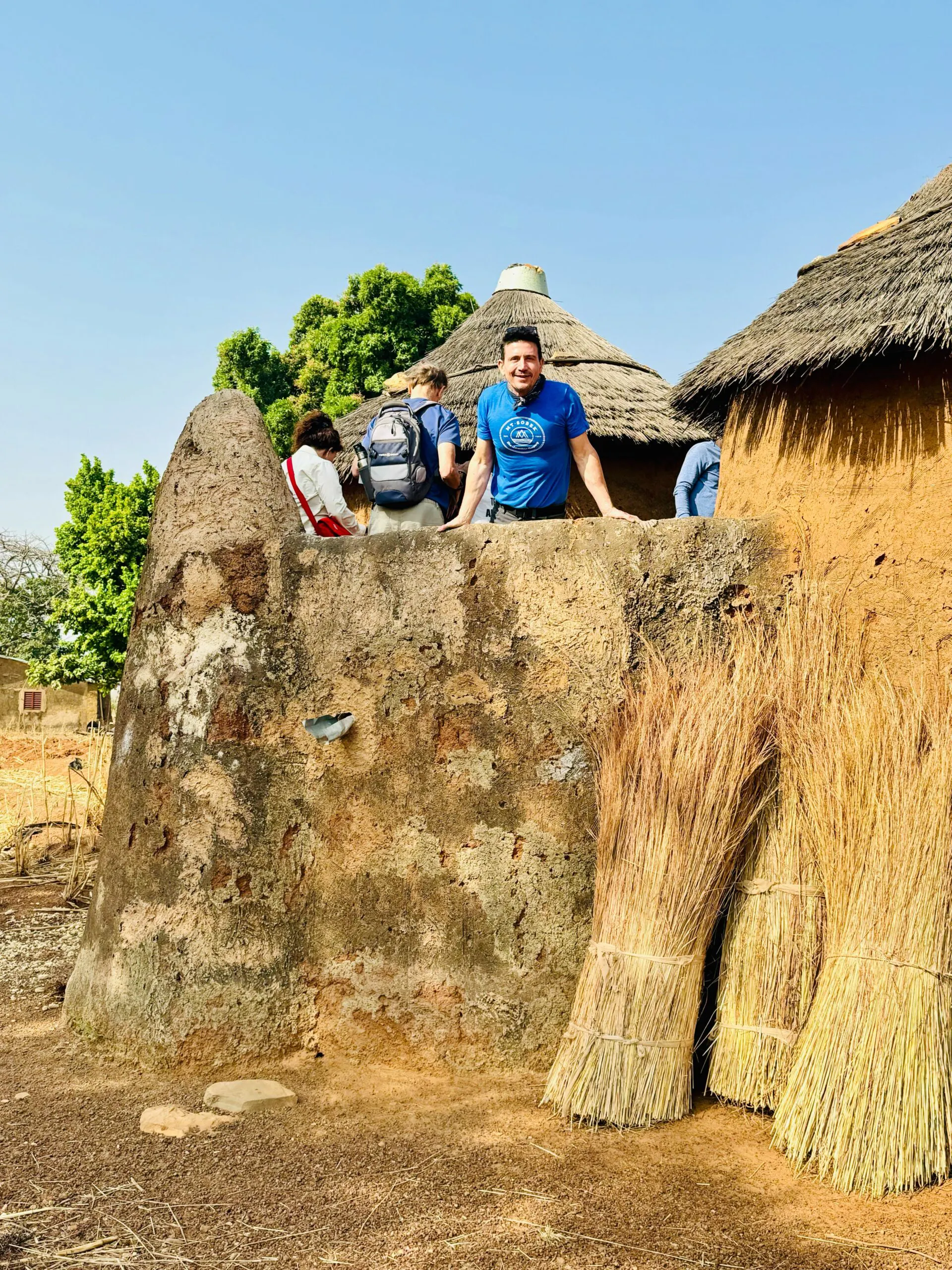 a solo male traveler peeking out from local African village during his cultural discovery tour in West Africa