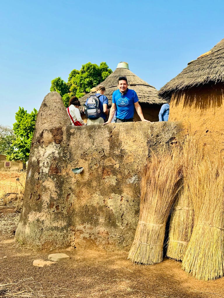 a solo male traveler peeking out from local African village during his cultural discovery tour in West Africa