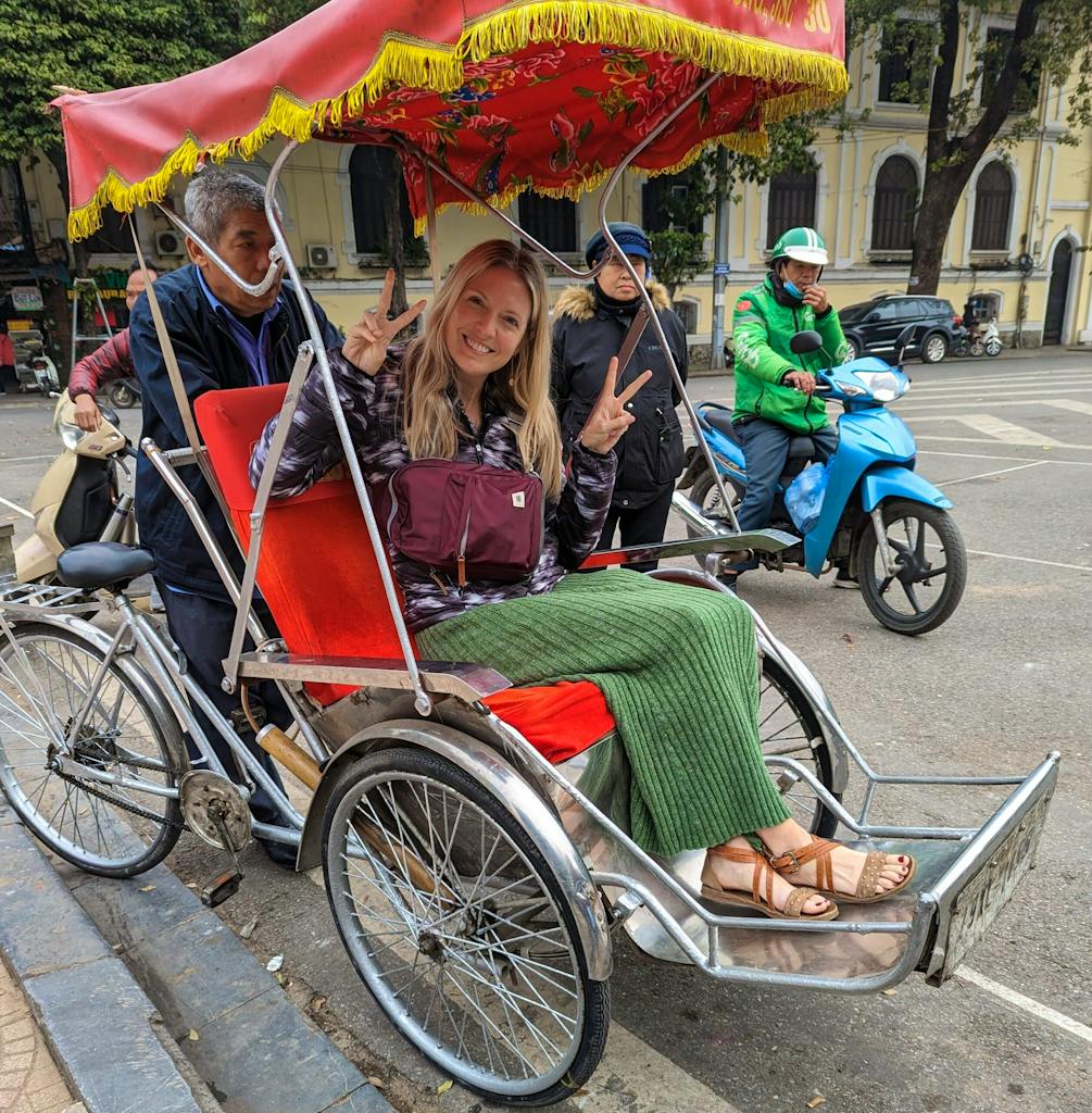 female traveler taking a rickshaw ride through bustling Old Quarter in Hanoi in Vietnam, Asia