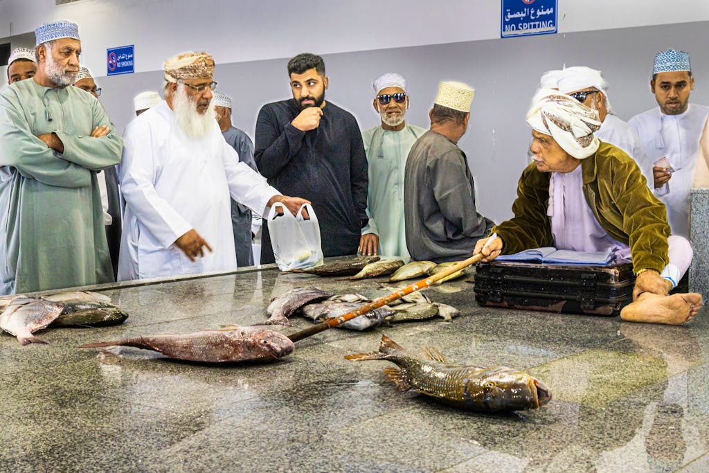local sellers haggling prices at marketplace with local villagers over fish in Oman in the Middle East