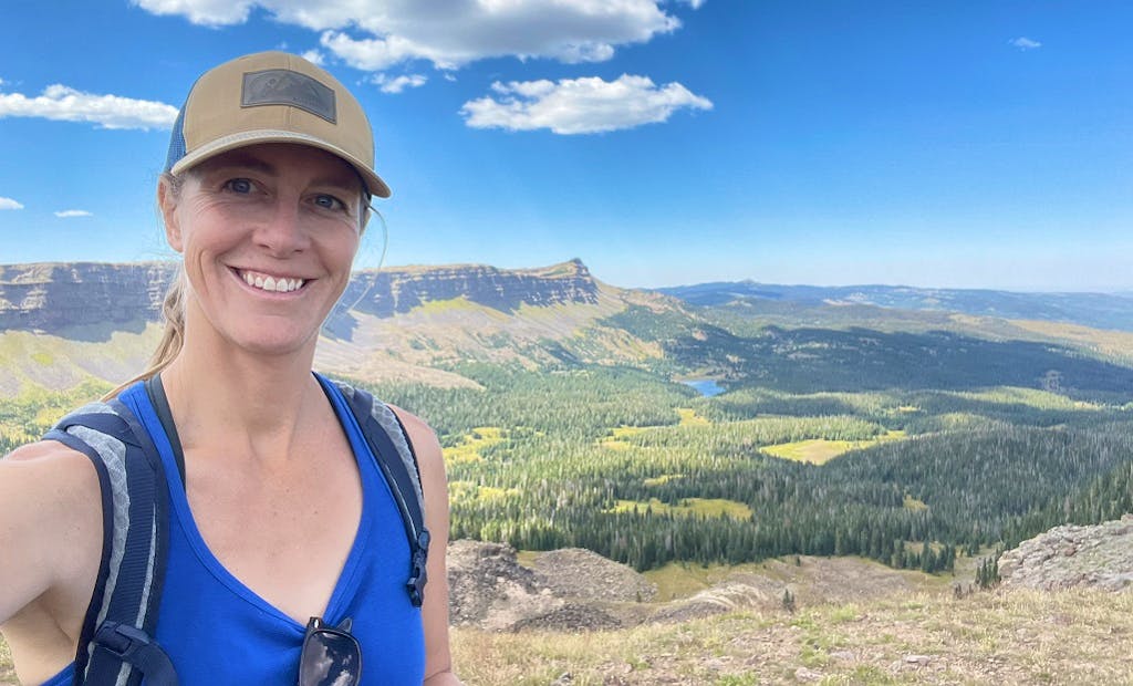 a woman hiker smiling in front of panoramic views on hike in North America