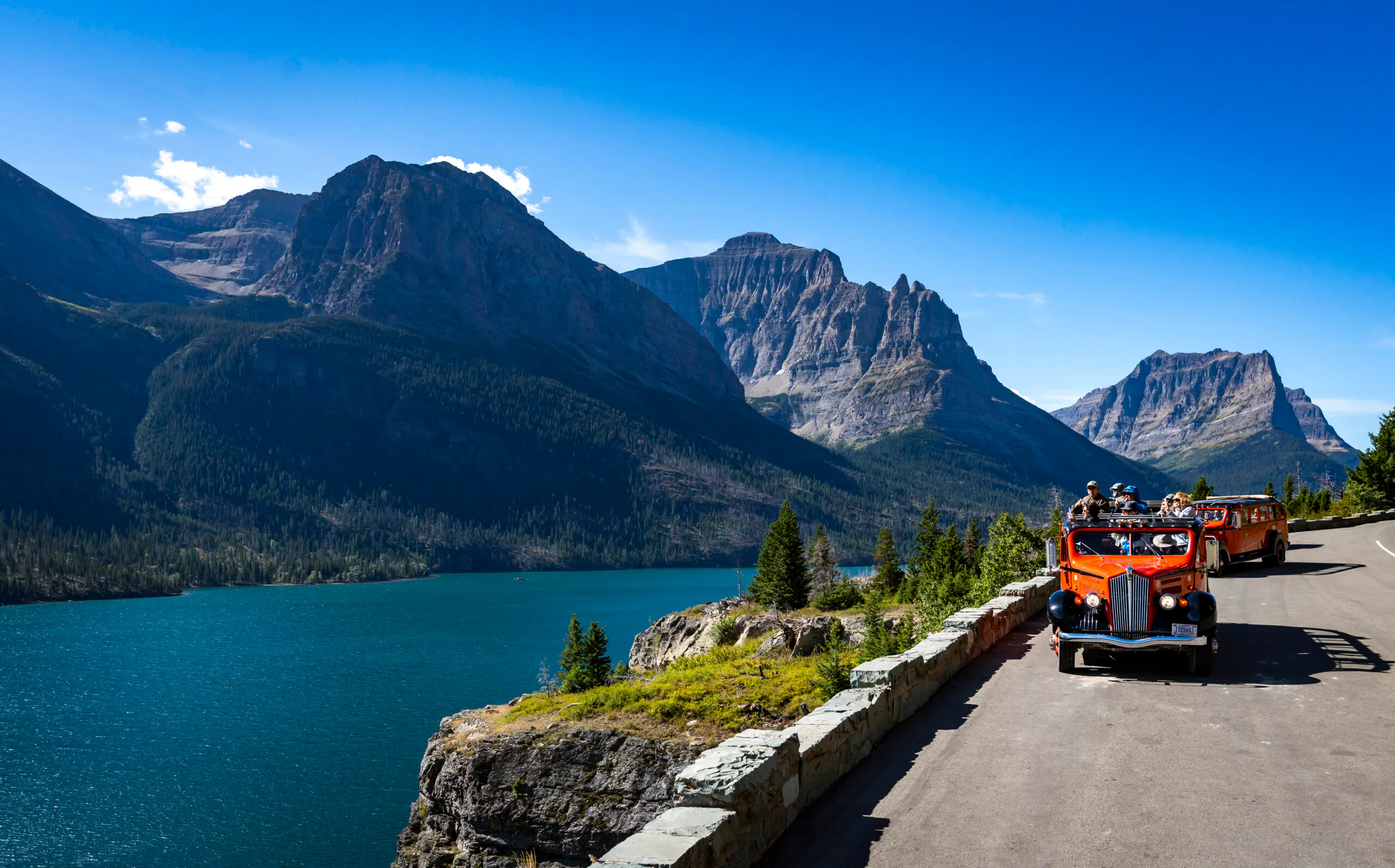 red bus driving in medicine road in Glacier National Park in Montana, USA