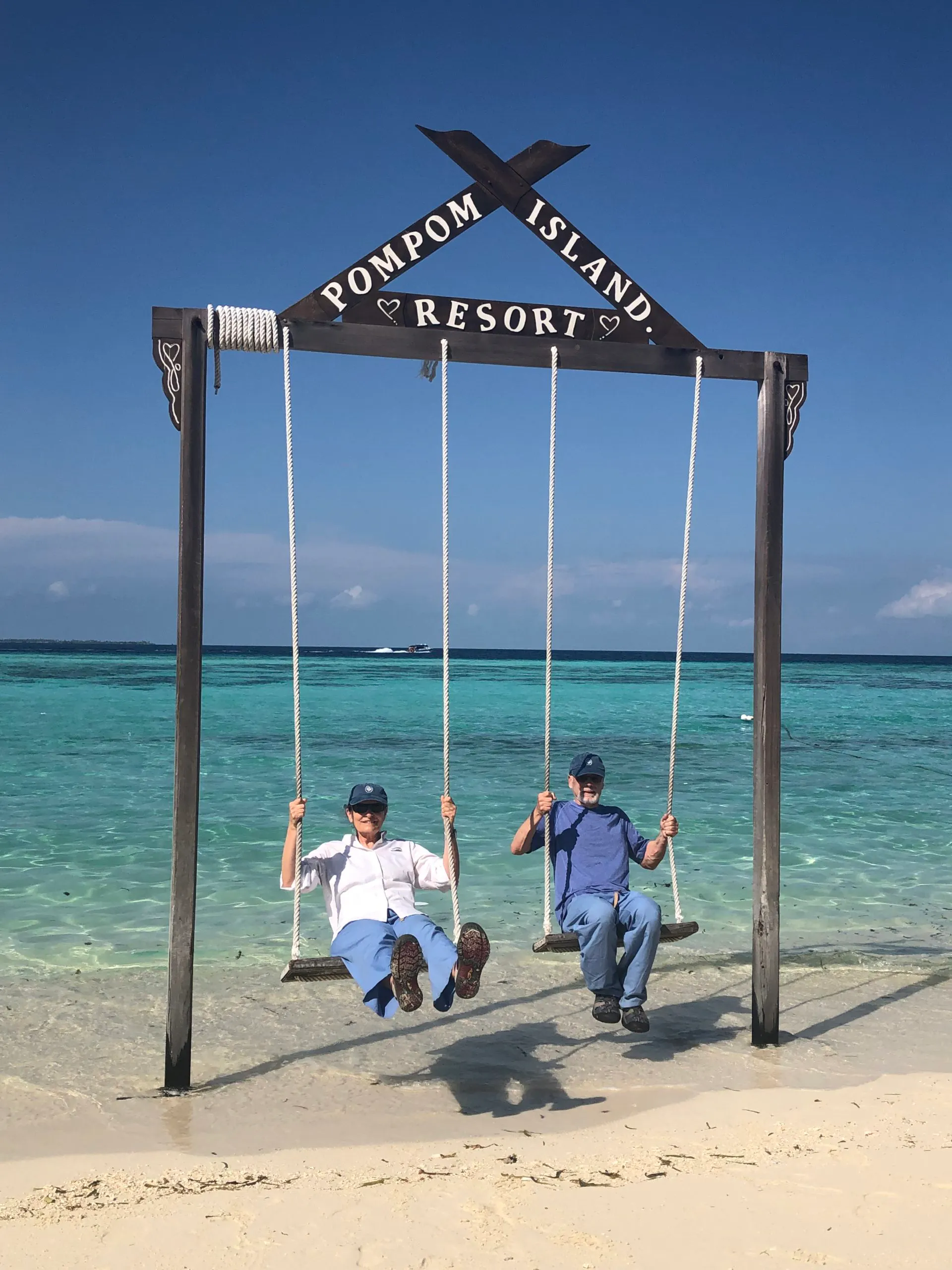 a couple of travelers having fun swinging on giant swing in Mataking Island known for its sandy beach and coral reefs in Borneo, Asia