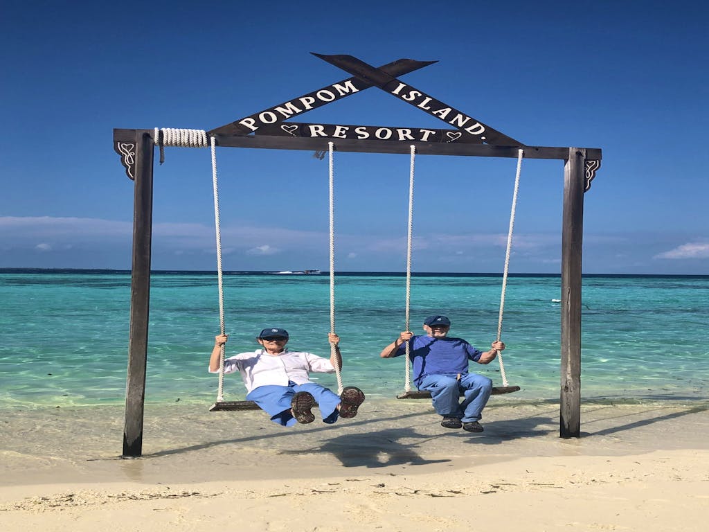 a couple of travelers having fun swinging on giant swing in Mataking Island known for its sandy beach and coral reefs in Borneo, Asia