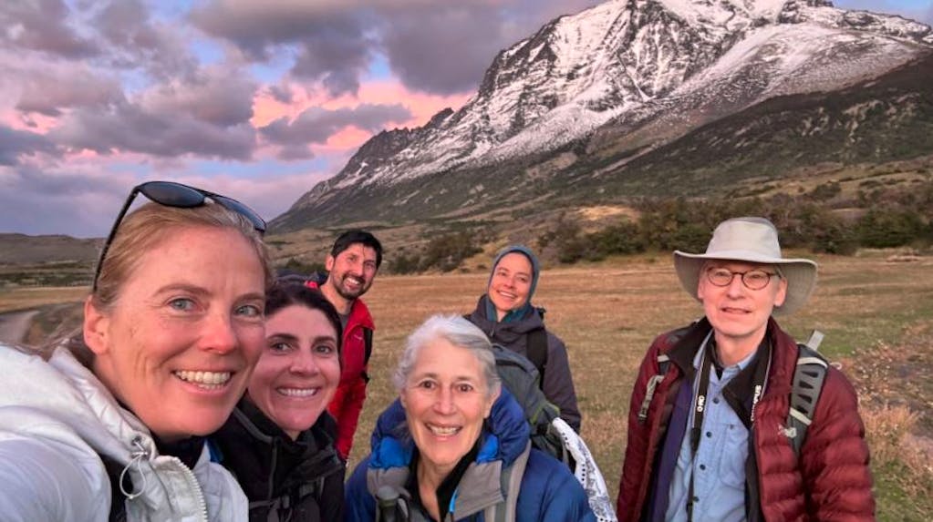 Group of hikers with Diane facing Patagonia breathtaking scenery during a sunset on a hiking trail