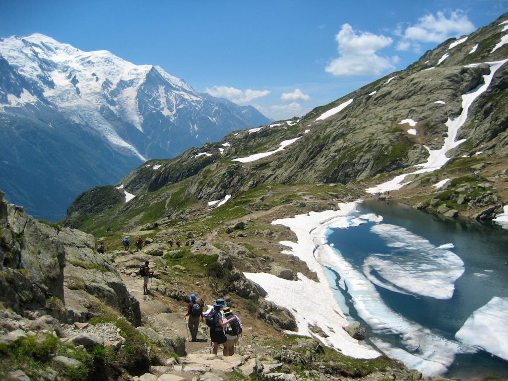 two travelers hiking trails near glaciers in Tour du Mont Blanc hiking circuit in the summer