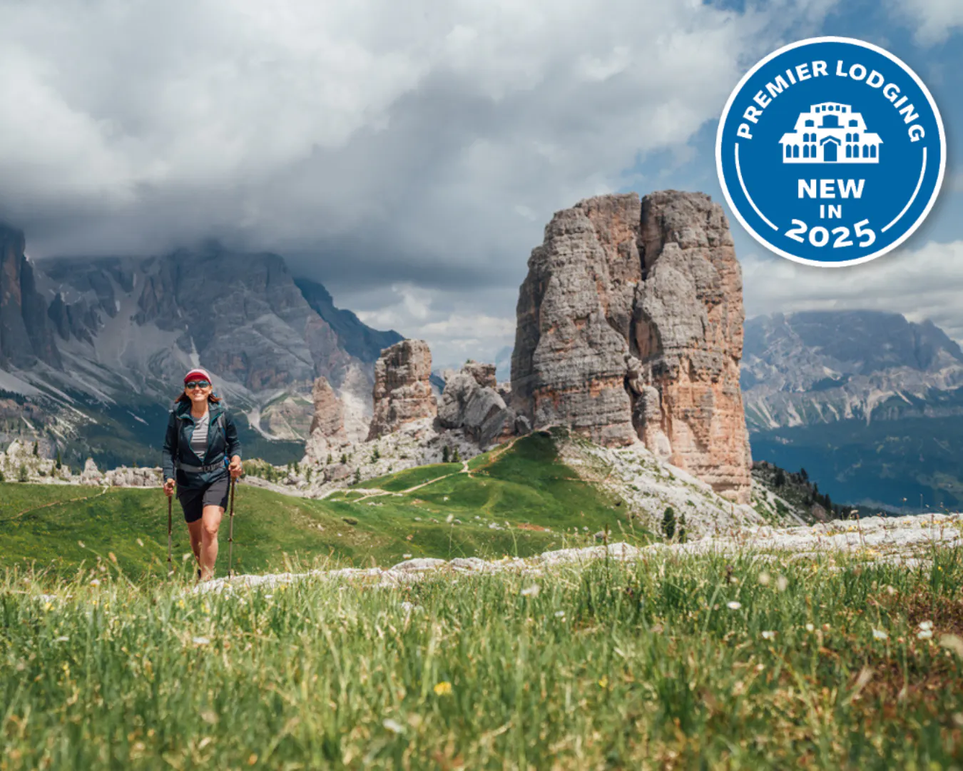 Smiling female trekker walking with backpack and trekking poles by green mountain hill with picturesque Dolomite Alps Cinque Torri formation on the background. Active people and mountains concept.