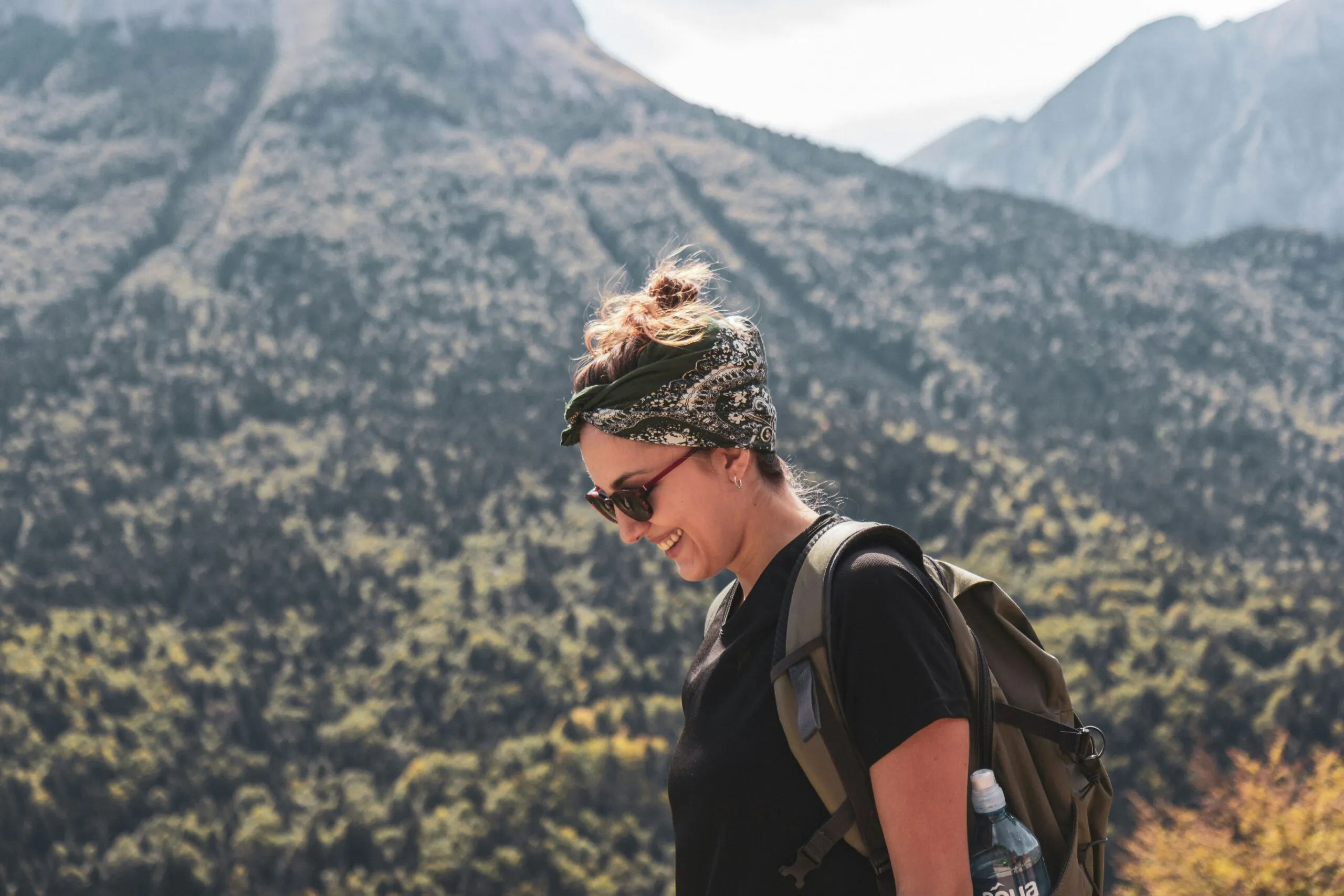 female hiker rucking on hiking daytrip with bandana on a sunny clear sky day