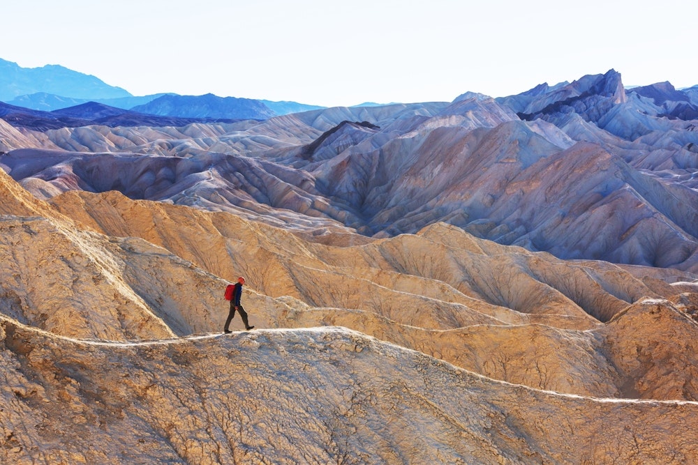 solo hiker in red hiking long rugged trails in winter at Death Valley National Park in California