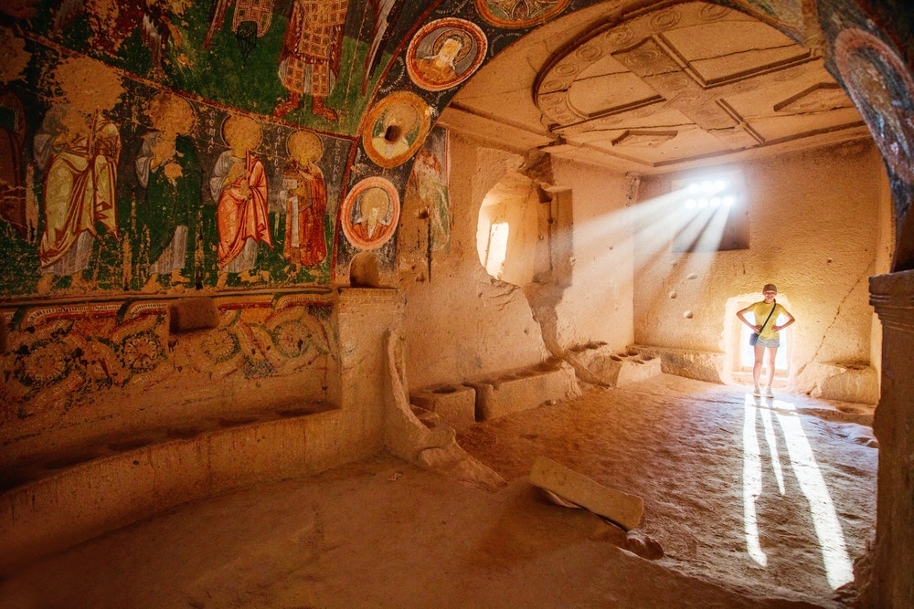 teenage girl exploring cave church in Cappadocia in Turkey, with ruins dating in 10th century